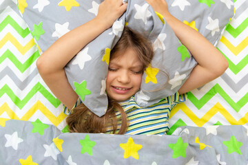 A little girl is lying in bed and is naughty, does not want to go to school.