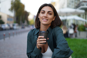 Woman with cup of coffee outdoor at city street at sunset happy smiling enjoying summer days