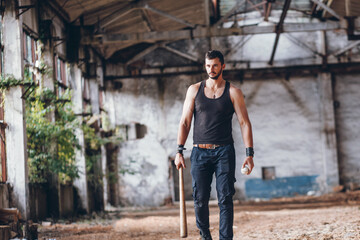 Strong Muscular Handsome Man in Black Tank Top with Baseball Bat in Empty Grunge Hall