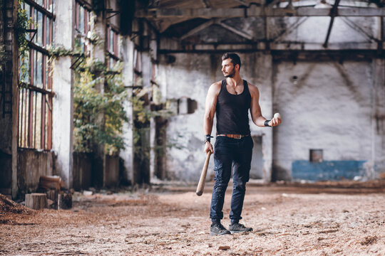 Strong Muscular Handsome Man in Black Tank Top with Baseball Bat in Empty Grunge Hall
