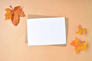 Invitation template with an envelope and autumn maple leaves on a beige background.