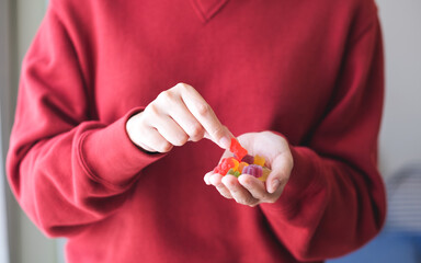 Closeup image of a woman holding and picking a red jelly gummy bear