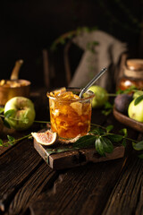 Close up of homemade apple jam with figs on wooden table in rustic style with vintage dishes.Dark mood.