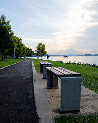 Riverside park in afternoon sun. Benches along waterfront park. Quiet waterfront park. resting area in park