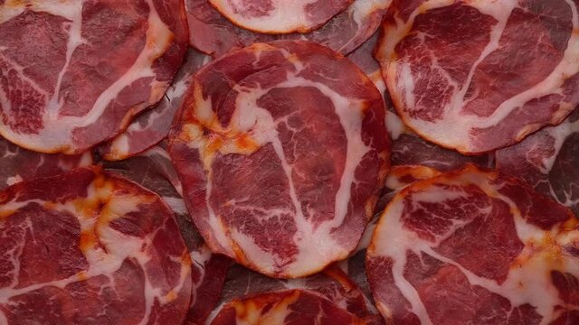 Sliced Spanish sausages Coppa or Capicola top view, rotation. 4K UHD video 