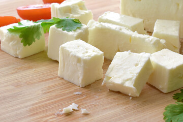 Feta cheese with cherry tomatoes and coriander on a bamboo chopping board.  The most famous Greek cheese. 