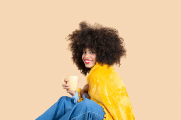 pretty afro woman woman covered with blanket while having coffee sitting
