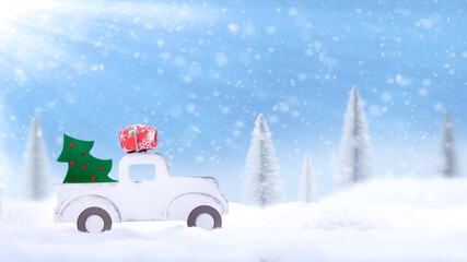 . Wooden toy car carrying a Christmas tree and gifts through a snowy forest in severe frost - Christmas concept