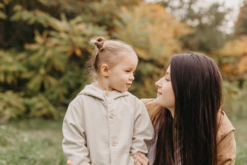 Young happy and smiling mom with her little daughter in arms hugging and kissing spending a weekend...