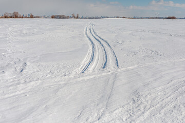 Fototapeta na wymiar Car tracks in the snow go into the distance. Wheel tracks on a snow road.