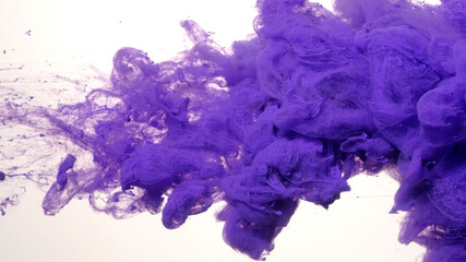 Awesome abstract background. Drops of purple ink in water. Purple watercolor ink in water on a white background. Colored acrylic paints in water.
