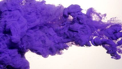 Drops of purple ink in water. Purple watercolor ink in water on a white background. Colored acrylic paints in water. Violet cloud of ink on a white background.