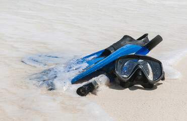 Mask and fins for scuba diving and snorkeling lie on the sandy shore against the backdrop of the...