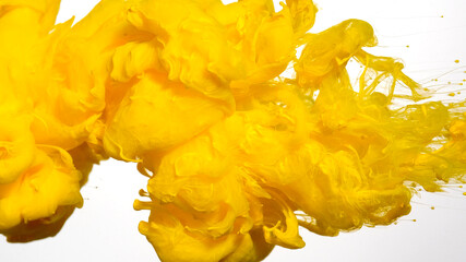 Awesome abstract background. Drops of yellow ink in water. Yellow watercolor ink in water on a white background. Colored acrylic paints in water.