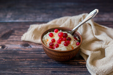 Clay bowl with sauerkraut and cranberries next to beige towel on wooden background