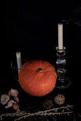 Orange pumpkin, glass candlesticks, extinguished candles. Halloween, evil forces are coming.
