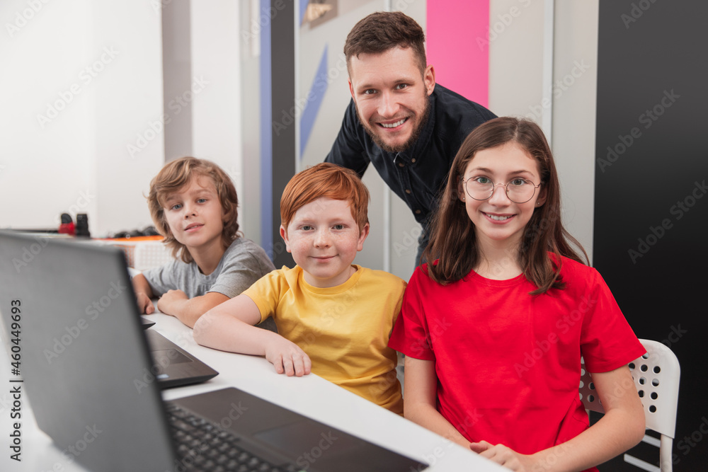 Wall mural group of pupils with teacher during computer class