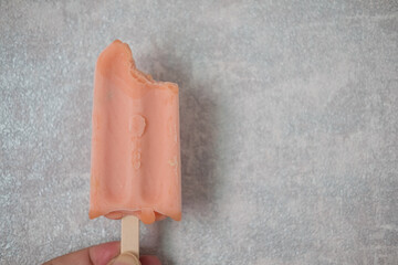 Cropped Image of person holding bitten pink popsicle.