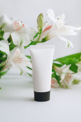 tube of moisturizer and alstroemeria on a white background close-up