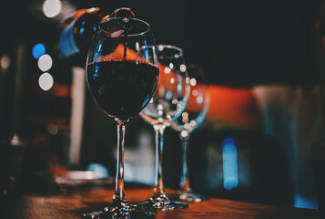 bartender pouring red wine into a glass in cafe or bar