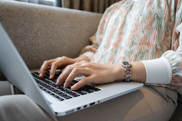 Happy Asian young woman making a video conference on laptop computer while living in the living room.