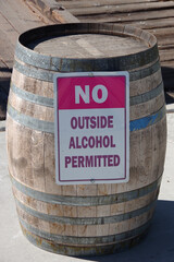 Sign NO OUTSIDE ALCOHOL PERMITTED affixed to a wine barrel at a winery tasting area