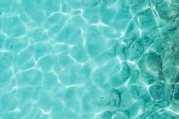 Water background, turquoise shallow sea water. Beautiful texture of sun glare on the water.