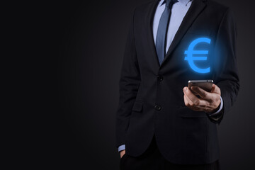 Businessman holds money coin icons EUR or Euro on dark tone background..Growing money concept for business investment and finance