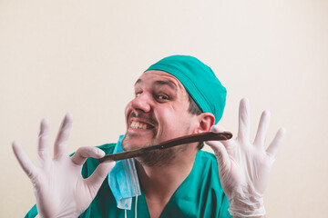 Young doctor in green surgeon suit and protective breathing mask with straight razor in hand...
