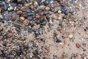 Water is washed up on a stony sandy beach, texture background wallpaper, stones and sand