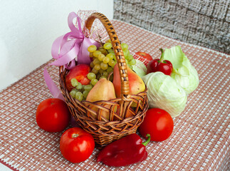 The basket is loaded with autumn gifts, pears, a bunch of grapes, apple, tomatoes, red pepper, white cabbage.