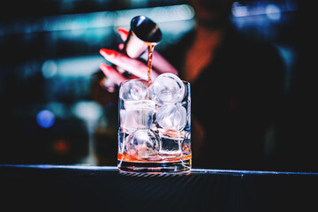 bartender making Cuba Libre cocktail in glass with ice and rum