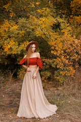 Fototapeta premium an attractive woman in a brown hat in the fall on a deciduous background. autumn trend
