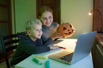 Fototapeta na wymiar Portrait of happy children who celebrate Halloween and communicate online using a computer. Traditional autumn holiday