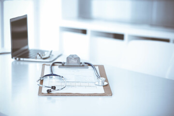 Stethoscope and clipboard with medication history records are on the table at the doctor's working place. Medicine and health care concept