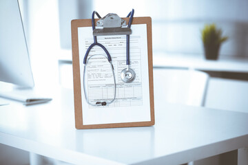 Stethoscope and clipboard with medication history records are on the table at the doctor's working place. Medicine and health care concept