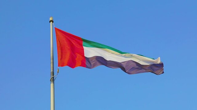 UAE or the United Arab Emirates Flag flying or waving high on a flag pole in the air. Blue sky in the background. Suitable for UAE National Day. HD Video.