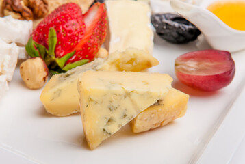 Cheese plate beautifully laid appetizer in a restaurant, Cheese, nuts and berries on a white background.
