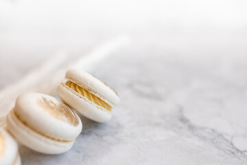 White macarons lie on a marble table. Delicious light cookies on a light background. Bakery