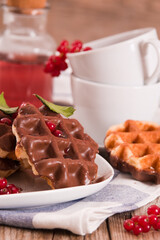 Waffles with chocolate topping, red currant and hazelnuts.