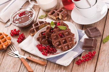 Waffles with chocolate topping, red currant and hazelnuts.