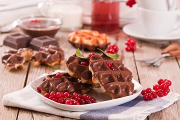 Waffles with chocolate topping, red currant and hazelnuts.