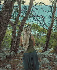 a rastafarian girl with dreadlocks walks on the rocks