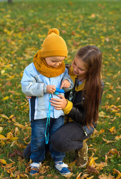 A little boy in a yellow cap with a camera shows the girl the photos he took on a beautiful autumn day
