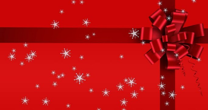 Animation of snow falling over ribbon on red background