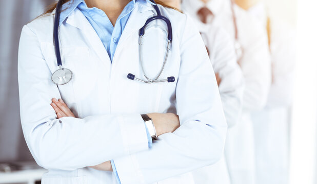 Group of modern doctors standing as a team with arms crossed in sunny hospital. Medical help, insurance in health care, best desease treatment and medicine concept