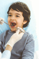 Little arab boy sitting at dental chair with open mouth during oral checking up with dentist doctor. Stomatology concept