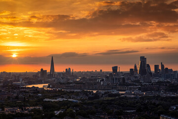 Wide panoramic view of the urban skyline of London, England, along the Thames river during a colorful sunset