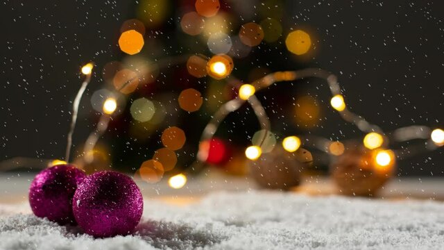 Animation of christmas bubbles over snow and bokeh garlands