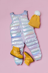 Warm pants hat and boots on pink background. Set of baby clothes for  winter. Fashion kids outfit.
